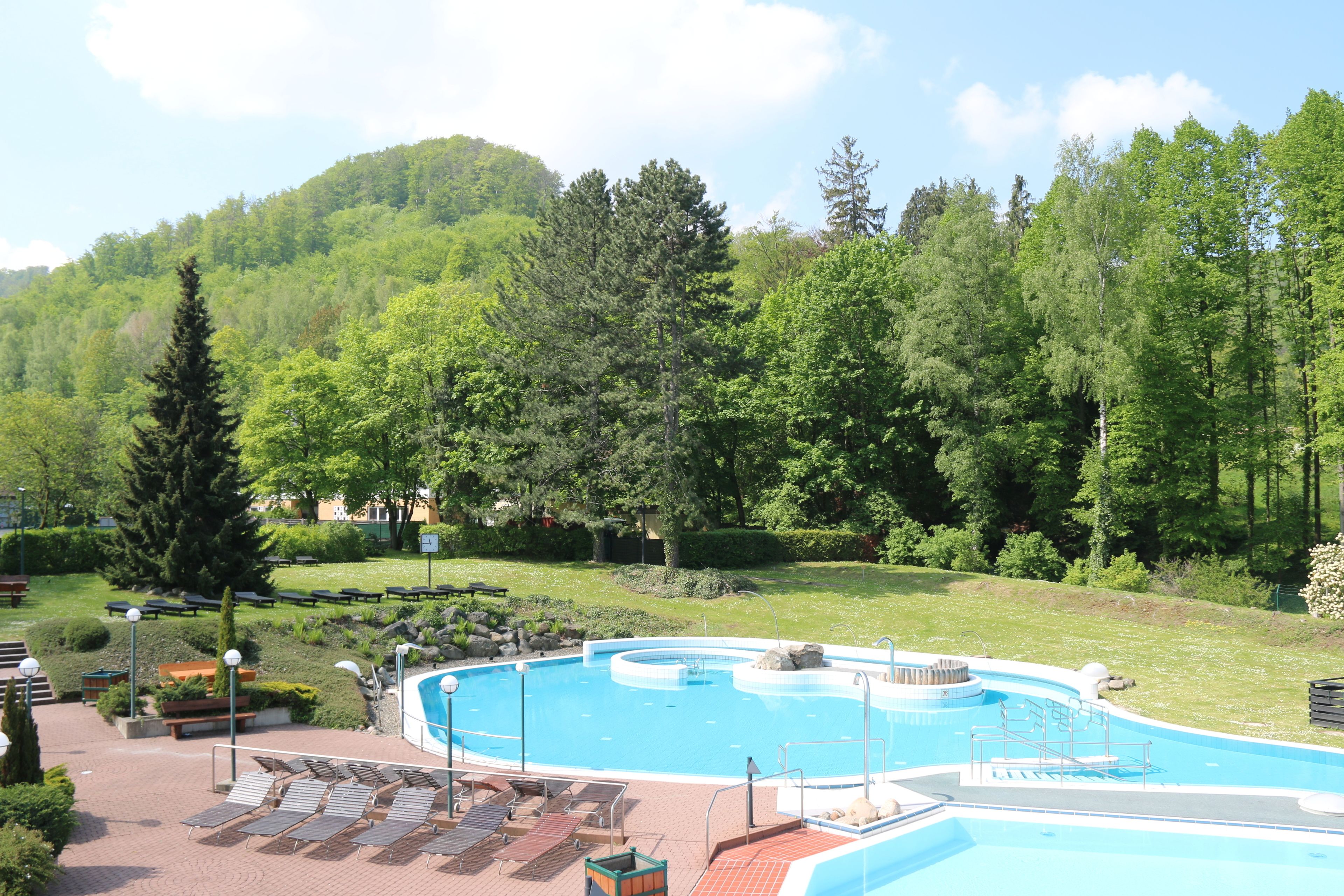 A swimming pool with a circular design, surrounded by lounge chairs and a landscaped garden.