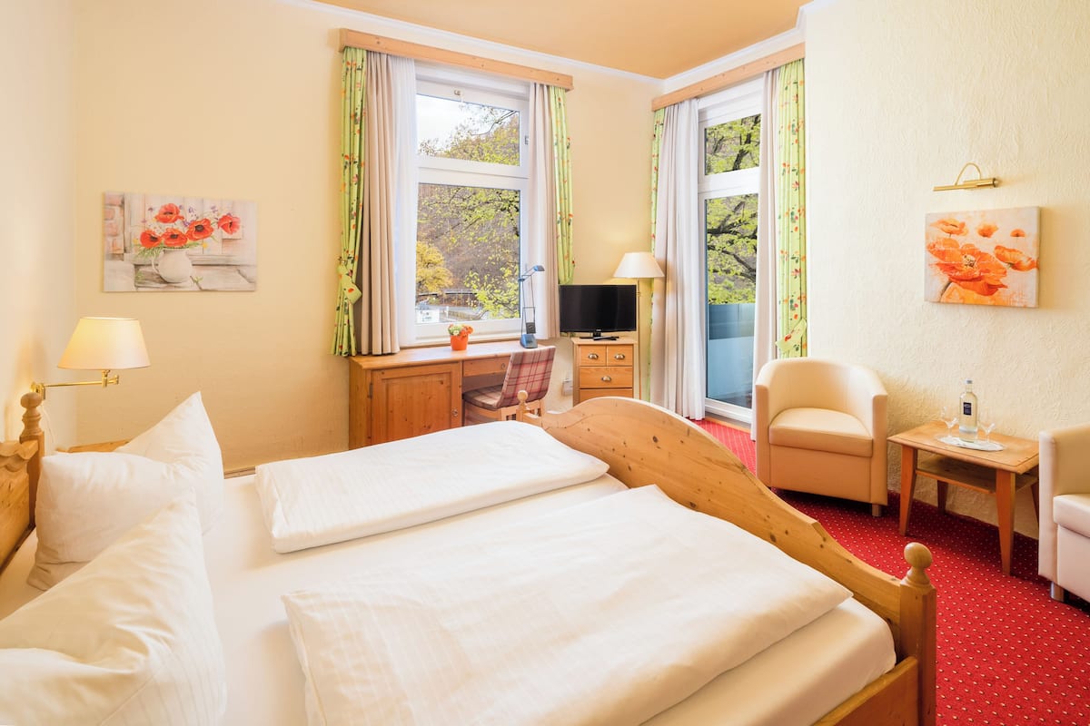 Une chambre d’hôtel avec un grand lit, un bureau avec une chaise, une télévision et une petite table avec une chaise.