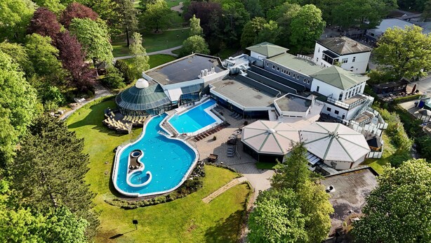 Vue aérienne d’un vaste domaine comprenant une piscine, plusieurs bâtiments et une végétation luxuriante.