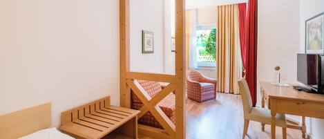 Una habitación con cama, escritorio, silla y televisor.