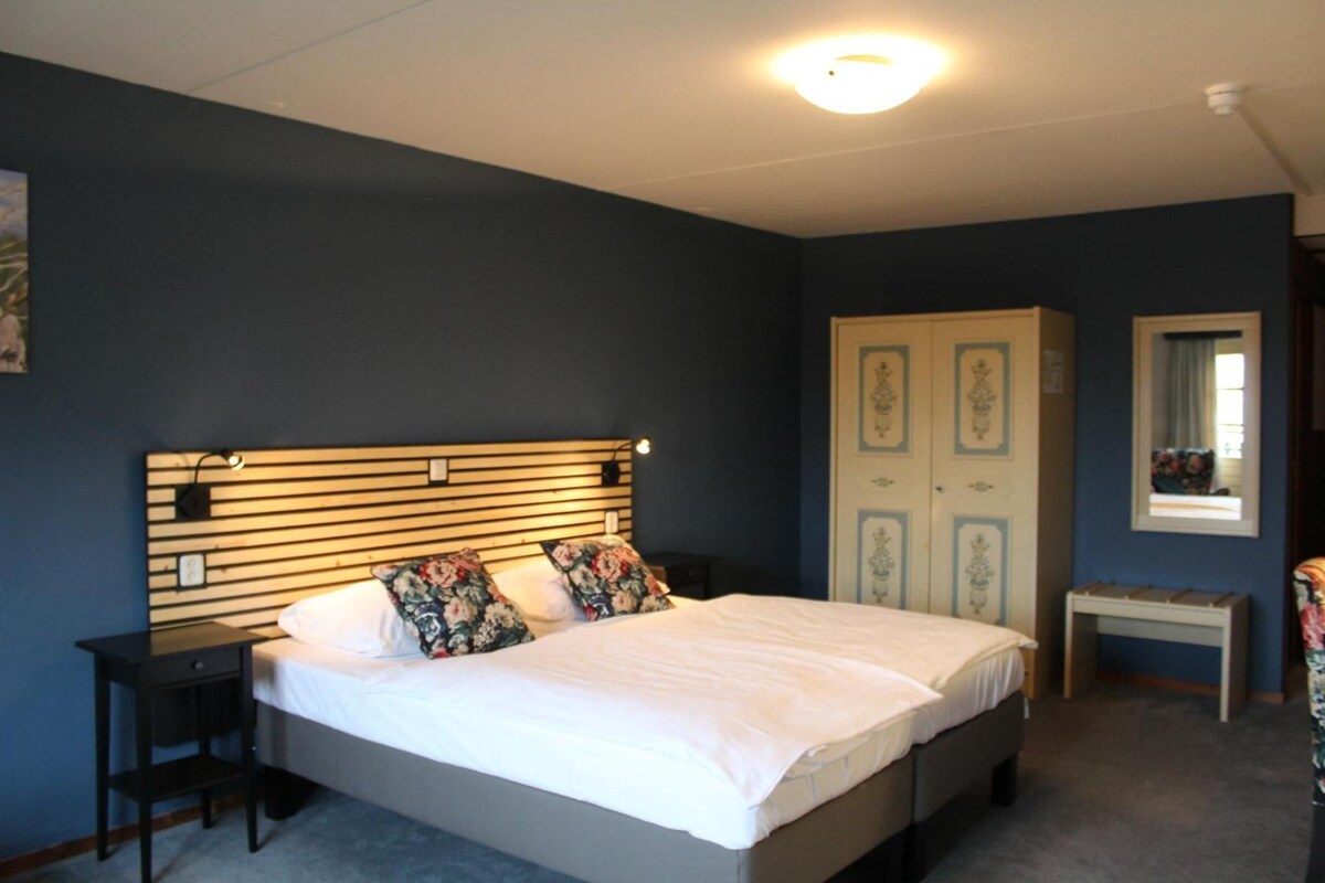 A bedroom with a bed, bedside tables, a wardrobe, and a mirror.