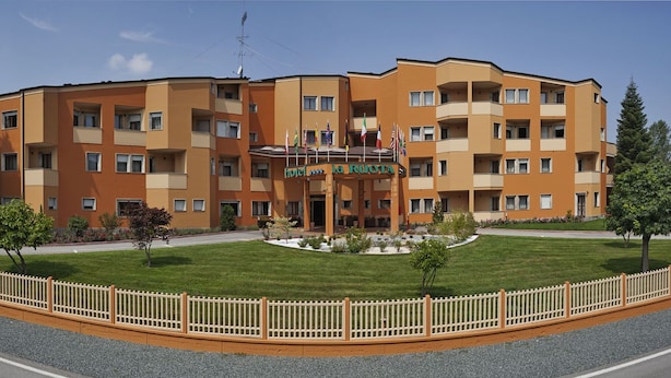 A multi-story hotel with a central courtyard, balconies, and a flag display. - Hotel La Ruota (Pianfei)