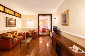 Una sala de estar con sofá, sillones, una mesa de centro, televisor y un mueble de madera.
