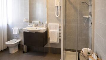 Une salle de bain moderne équipée d’une douche, de toilettes, d’un bidet et d’un meuble-lavabo avec un évier et un porte-serviettes.