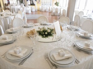 A banquet hall with round tables set for a formal event, complete with place settings, wine glasses, and floral centerpieces. - Phi Hotel Pianfei (Pianfei)