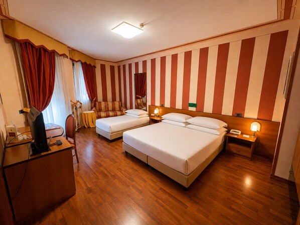 Habitación de hotel con dos camas, un escritorio, una silla, un televisor y un espejo.