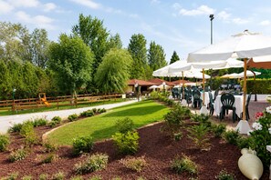 An outdoor dining area with tables and chairs, surrounded by greenery and trees. - Phi Hotel Pianfei (Pianfei)