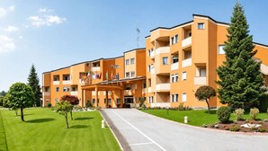 A multi-story hotel with a central entrance, balconies, and a well-maintained lawn.
