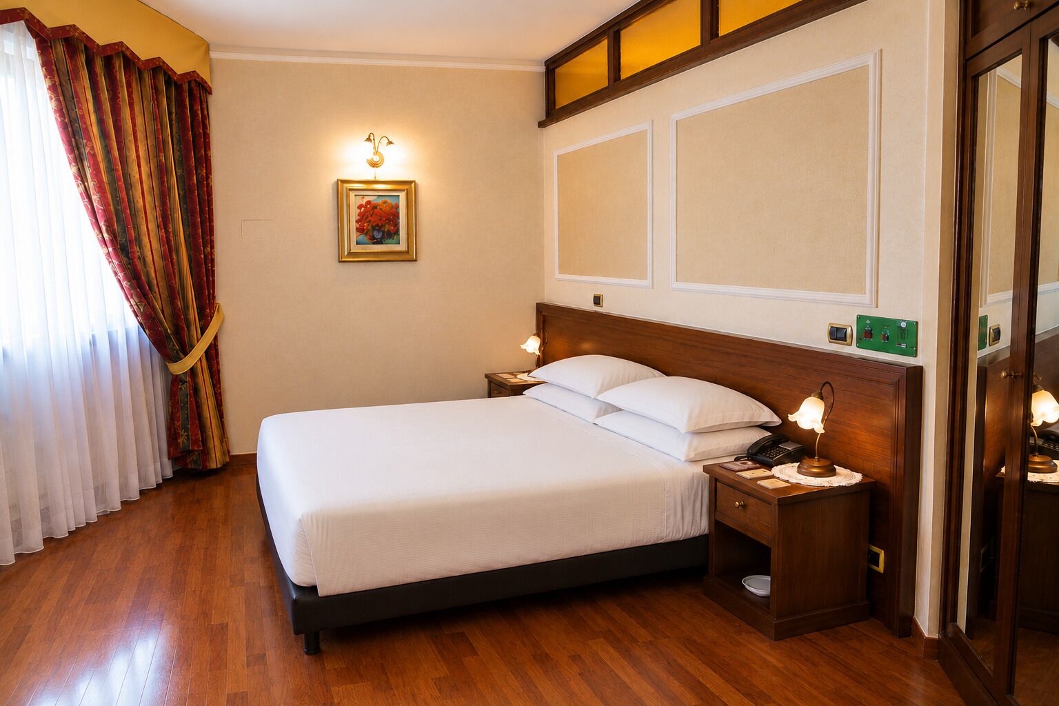 A hotel room with a large bed, bedside lamps, a telephone, and a wall-mounted light fixture.