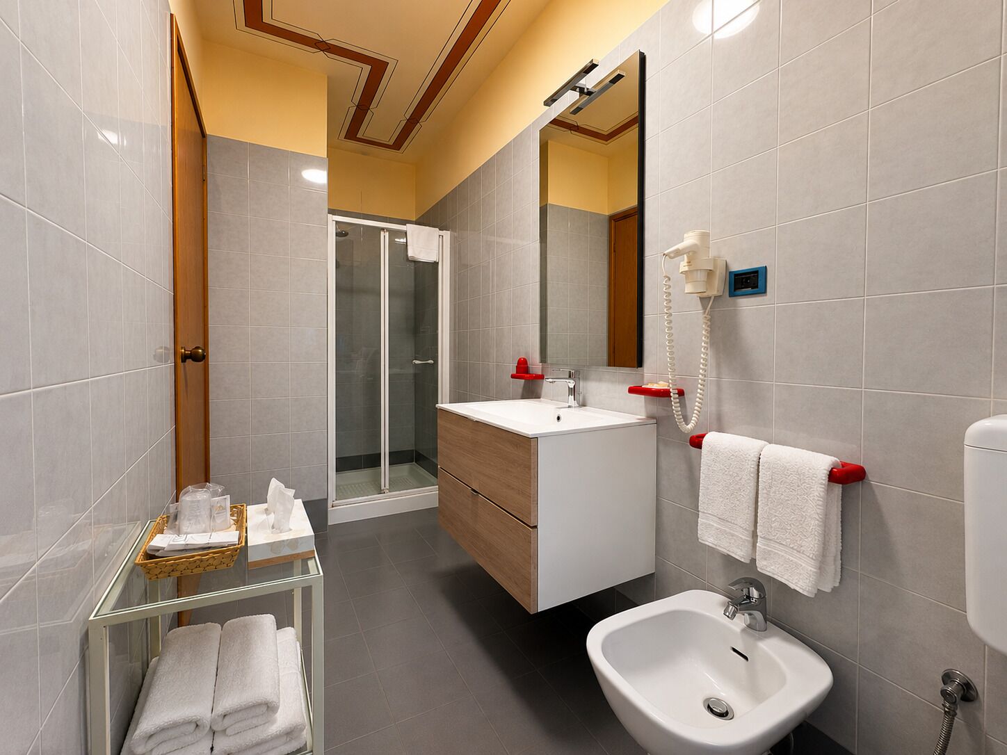 Ein modernes Badezimmer mit Duschkabine aus Glas, einem weißen Waschbecken, einem Bidet und einem Waschtisch mit Spiegel.