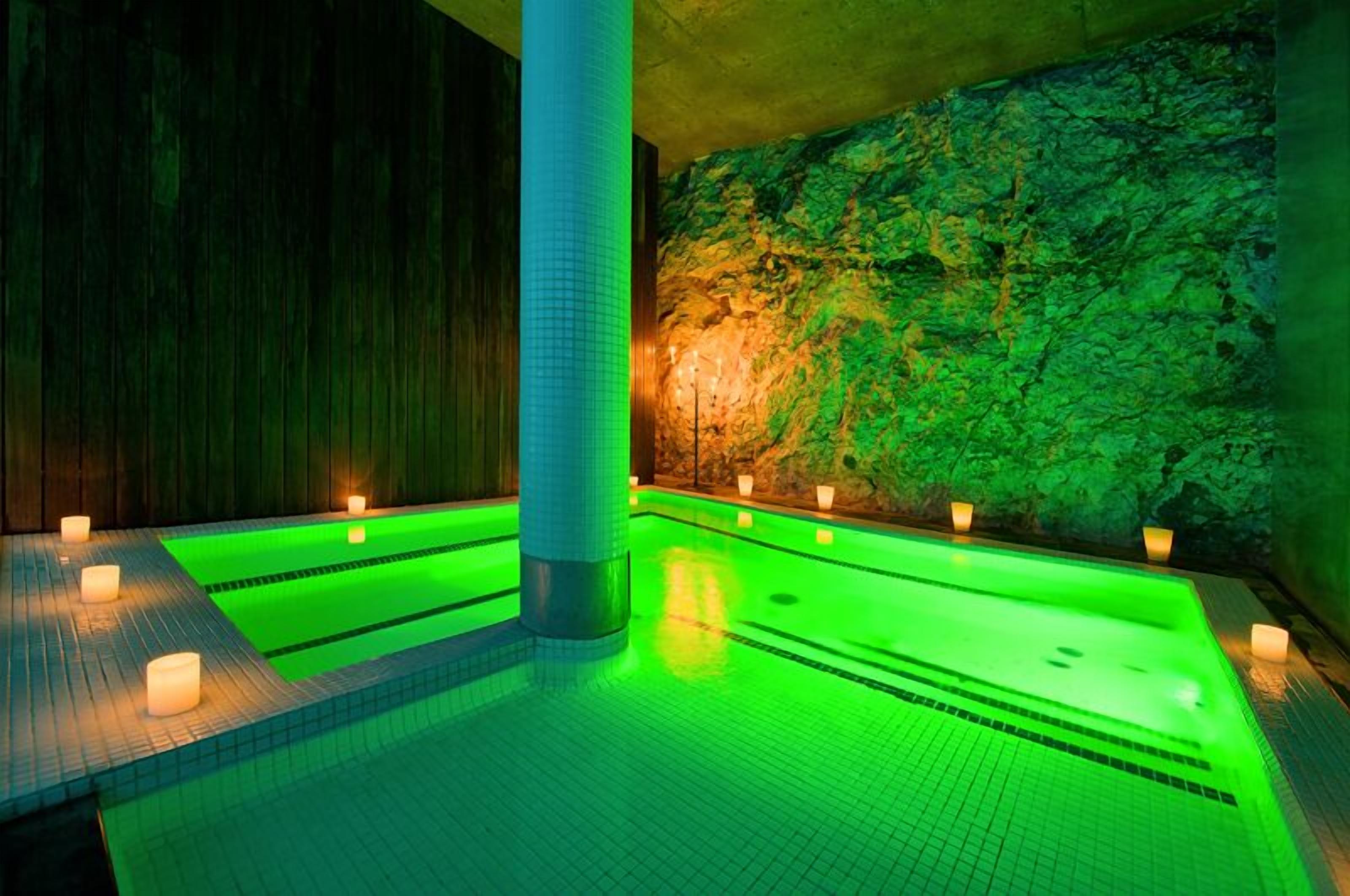 A spa area with a large pool, stone walls, and candles.