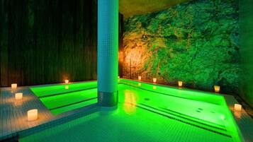 A spa area with a large pool, stone walls, and candles.