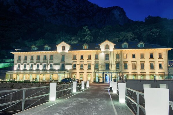 Un hotel grande de varios pisos con fachada simétrica, numerosas ventanas y un área de acceso cubierta.