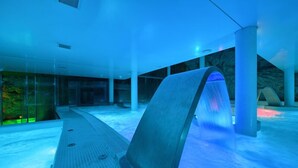 Ein moderner Innenpoolbereich mit Glasveranda und Wasserspiel.