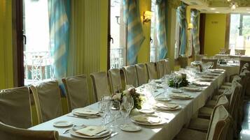 A long dining table set for a formal event with chairs, tablecloths, and glassware.