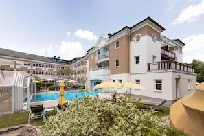 A hotel with a swimming pool, outdoor seating, and a covered patio area. - Hotel TraumVogel (Jennersdorf)
