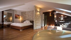 Un dormitorio moderno con una cama grande, una pared de acento de piedra y una mesa de centro de vidrio.