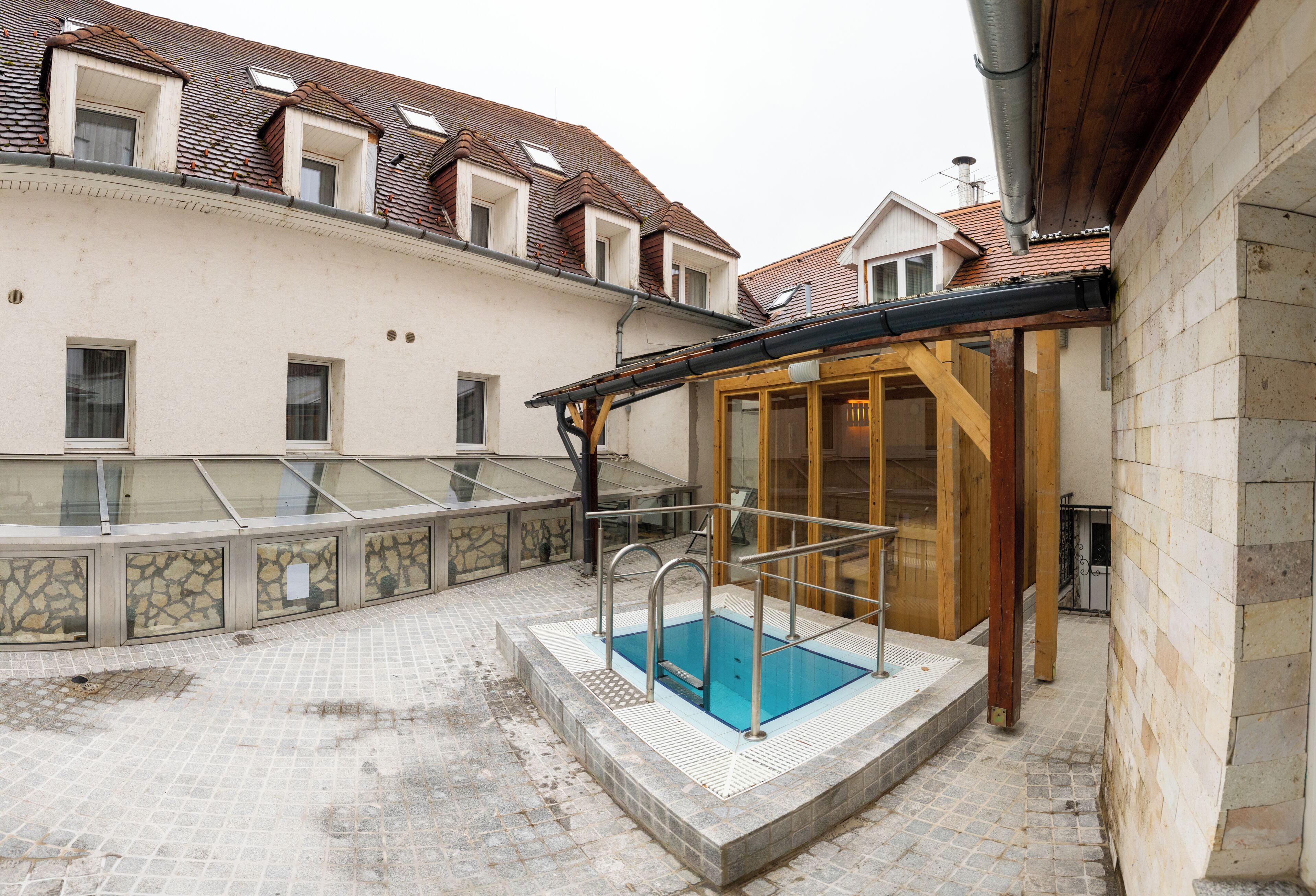 A swimming pool with a glass enclosure, surrounded by stone walls and a tiled floor.