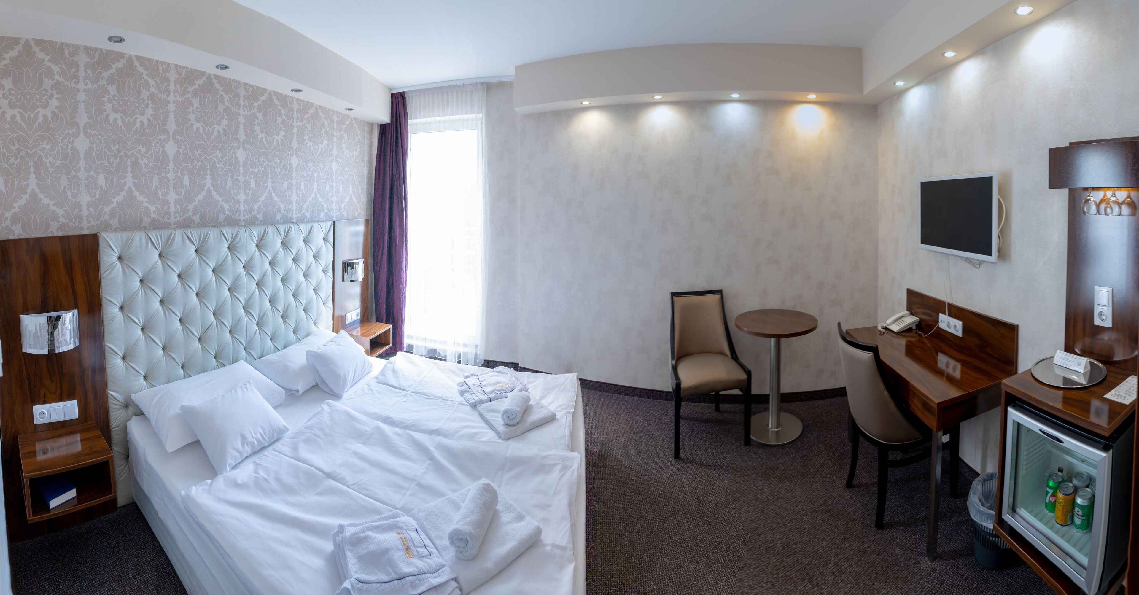 Habitación de hotel con una cama grande, un escritorio, una silla y un televisor.