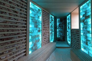 Un couloir aux murs de pierre et aux lambris en bois, qui mène à un espace détente.