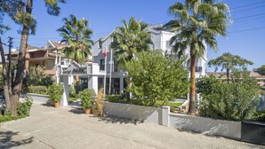 A modern building with a white facade, large windows, and a balcony. There are palm trees and potted plants in the surrounding area. - Forest Park Hotel (Kemer)