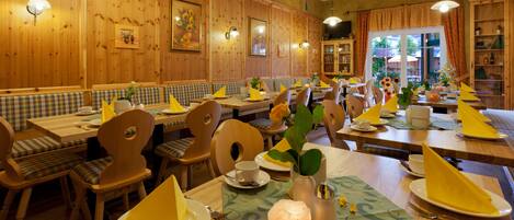 Un restaurante con paneles de madera, varias mesas para comer con servilletas amarillas y sillas de madera.