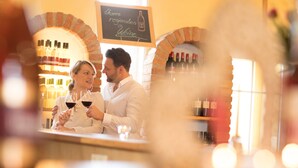 Una coppia in un bar con una vetrina di vino e una lavagna.
