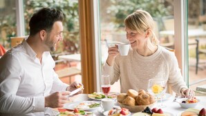 Un tavolo da pranzo con diversi piatti, tra cui frutta, pane e un bicchiere di vino rosso.