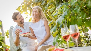 Una coppia seduta all'aperto con una pizza e bicchieri di vino.