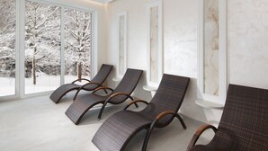 Un cuarto de spa con tres sillones de mimbre, ventanas amplias y decoración mural de mármol.