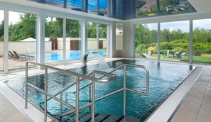 An indoor swimming pool with clear views of a backyard pool and lush greenery. - Francis Palace Hotel (Frantiskovy Lazne)