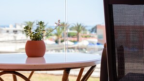Una mesa redonda con una planta en maceta y una silla con respaldo de malla.