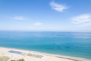 A beach with clear blue water, a sandy shore, and umbrellas arranged for sunbathing. - Rethymno Village (Rethymno)