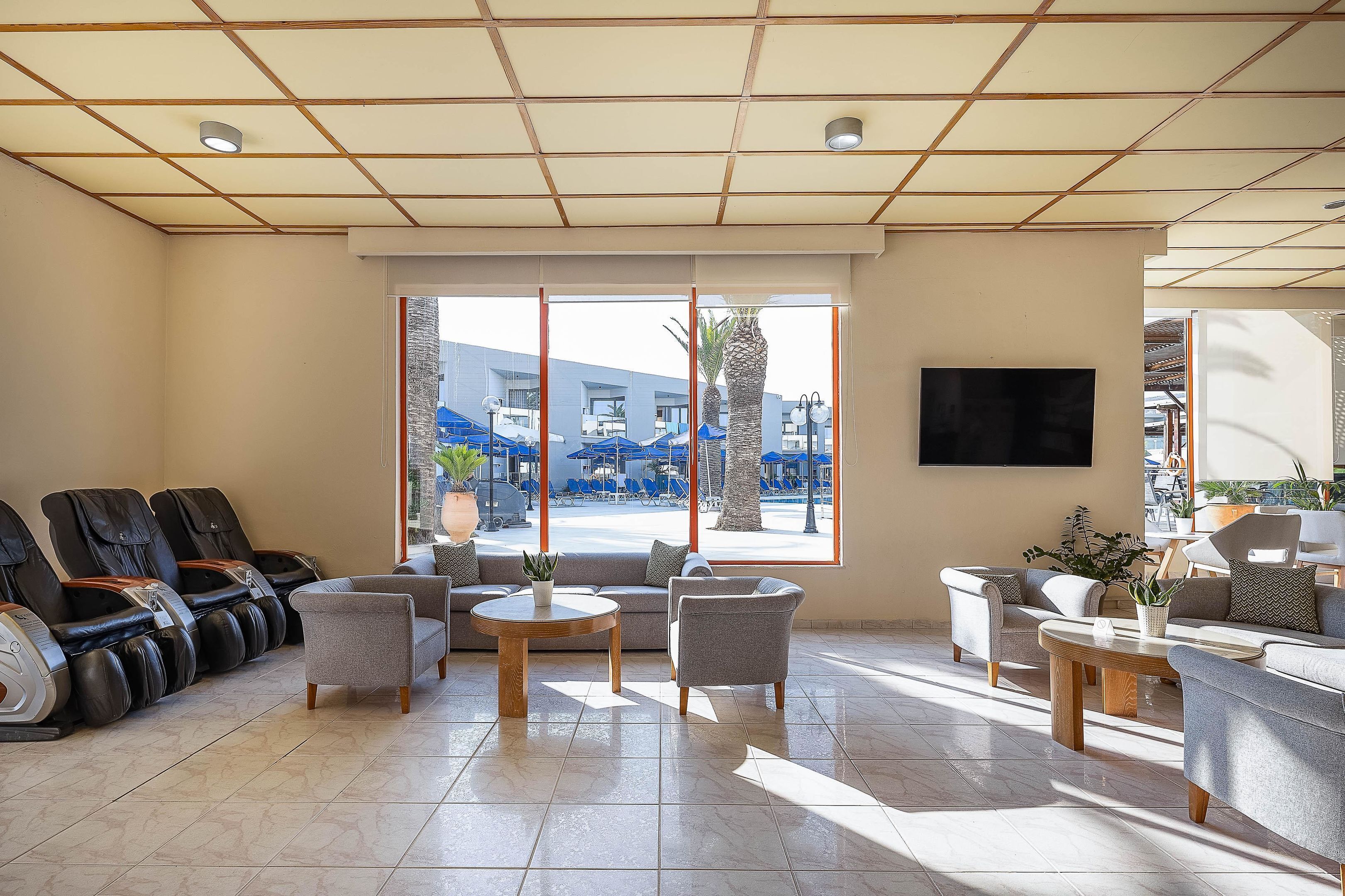 A modern lounge area with massage chairs, sofas, and a TV screen.