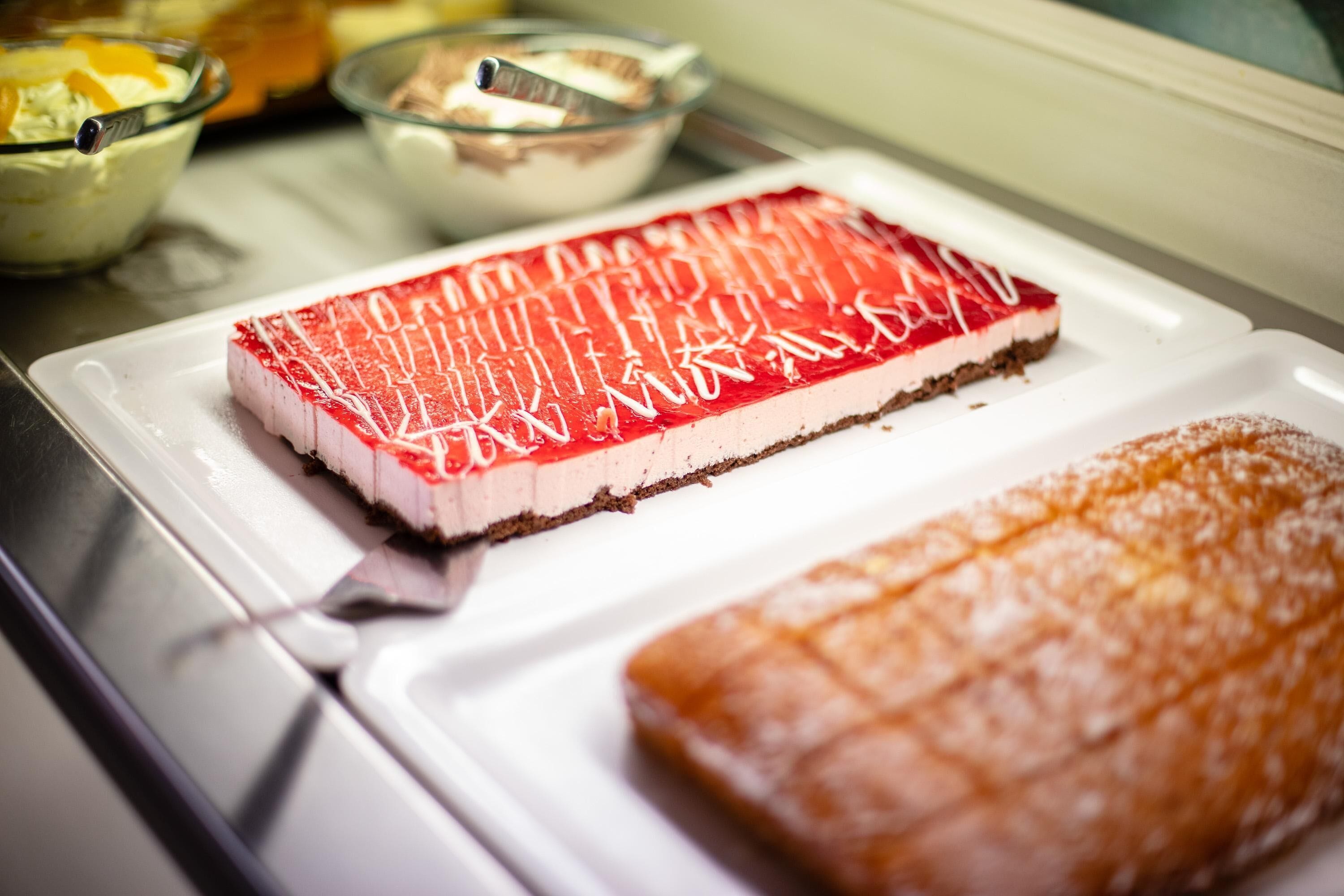 A dessert tray with a red and white layered cake and a brown pastry.