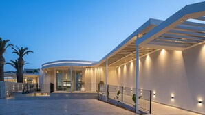 Un edificio moderno con fachada curva, un área exterior cubierta y una escalera que conduce a una entrada.