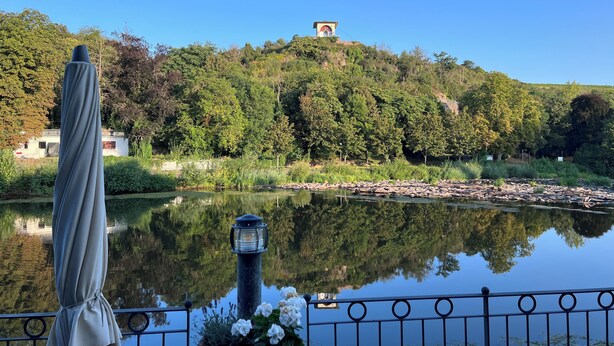 A serene lakeside view with a gazebo, a lamp post, and a hill with a structure on top. - Hotel Victoria (Bad Kreuznach)