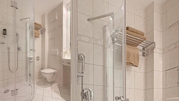 Un baño moderno con cabina de ducha de vidrio, inodoro y lavamanos.