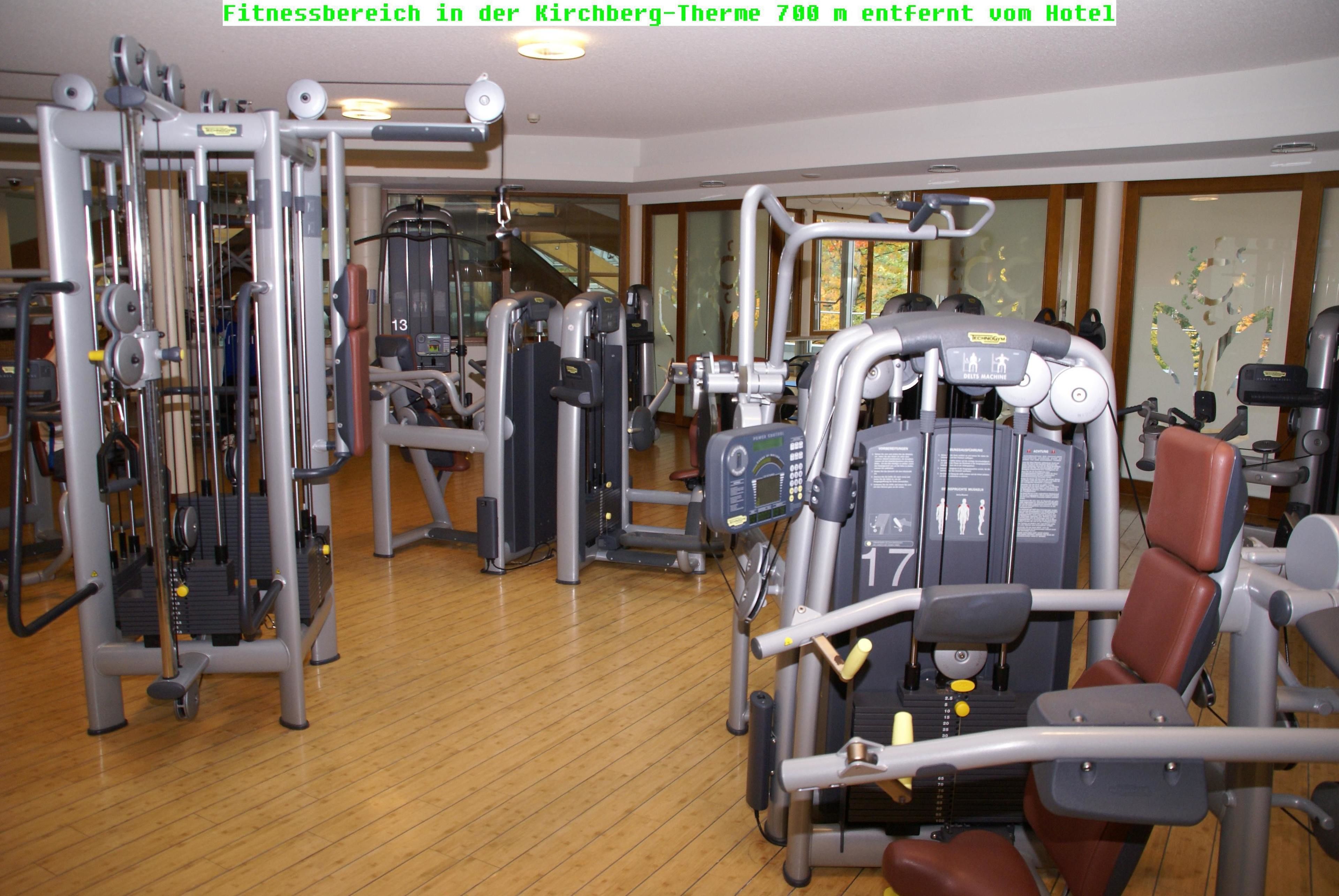 Et fitnessrum med forskellige træningsmaskiner, herunder en benpress og en brystpress, i et hotel.