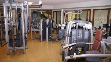 Et fitnessrum med forskellige træningsmaskiner, herunder en benpress og en brystpress, i et hotel.