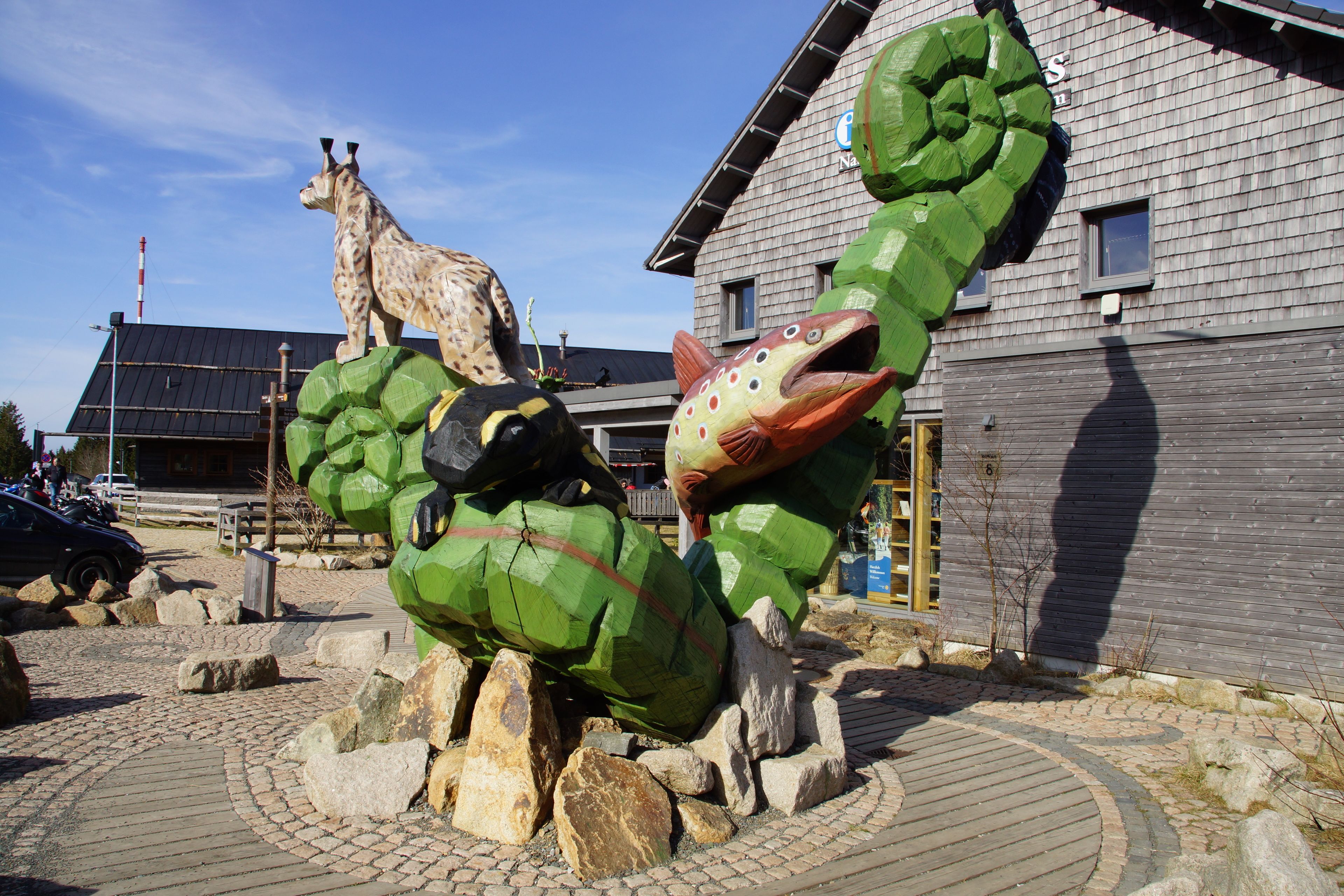 A sculpture of a giraffe and a fish in front of a building with a wooden facade.