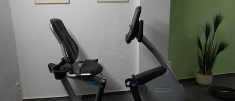 An exercise bike in a room with a green wall and two framed pictures.