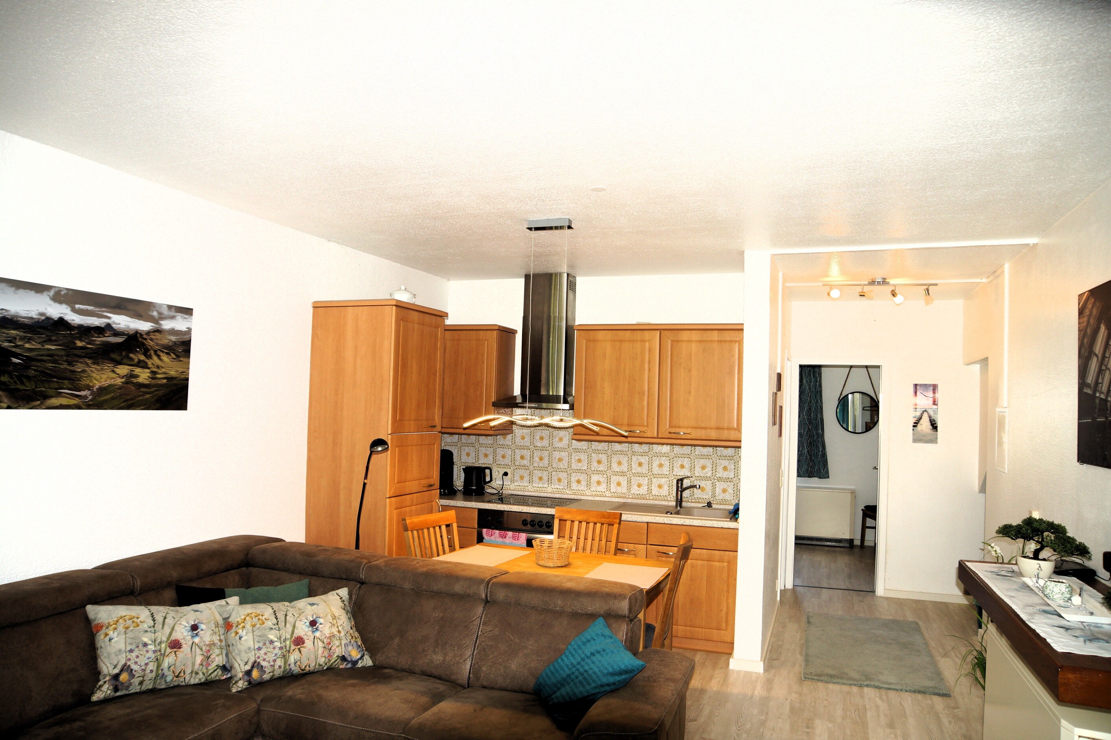 A compact living space with a kitchenette, a dining area, and a seating area with a sofa and chairs.