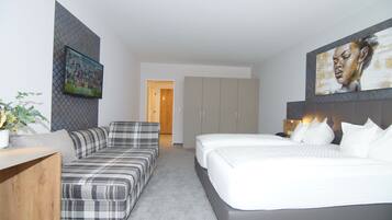 A modern hotel room with a sofa, a bed, and a painting on the wall.