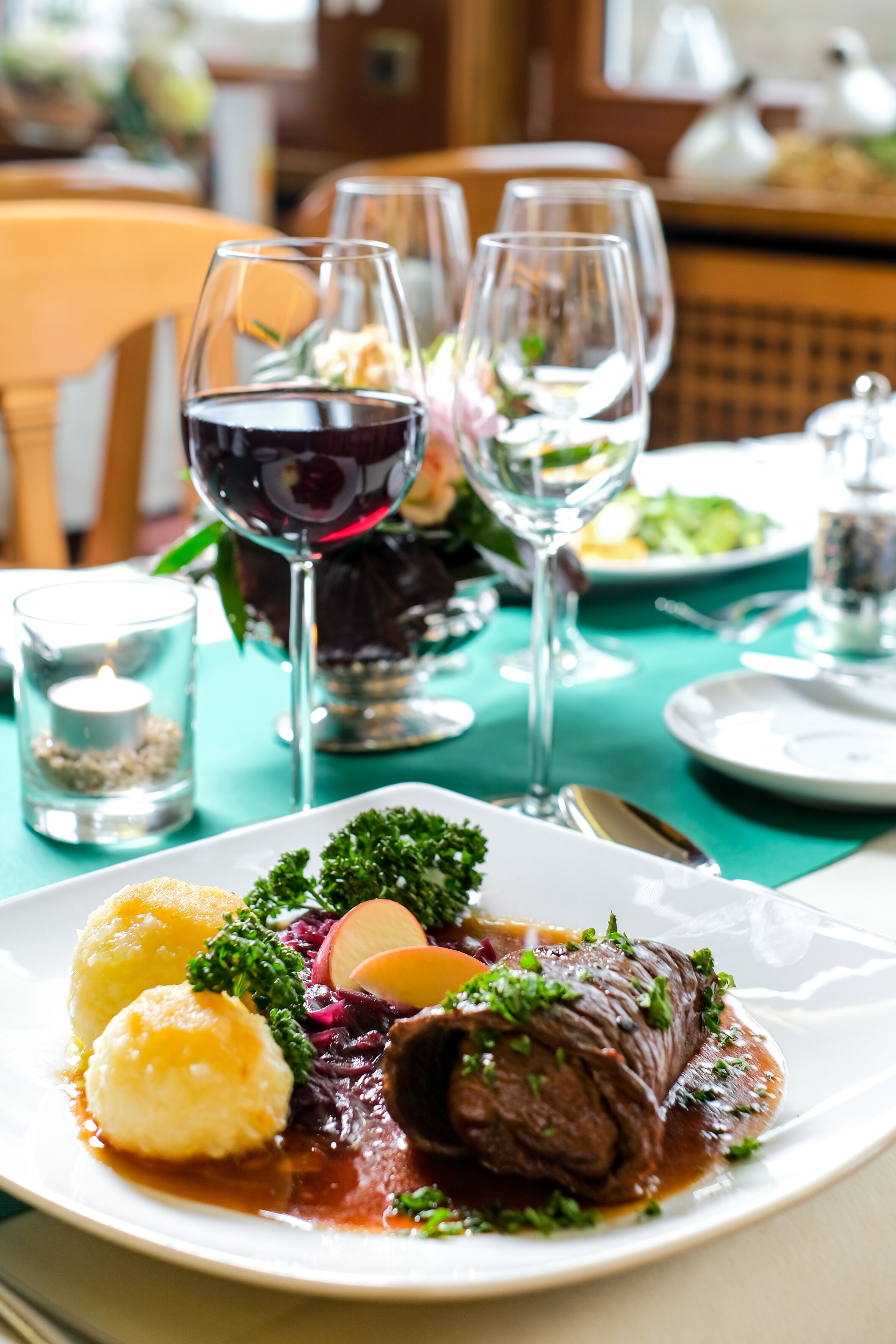 Una mesa de comedor elegantemente dispuesta con un plato de comida, copas de vino y una vela.