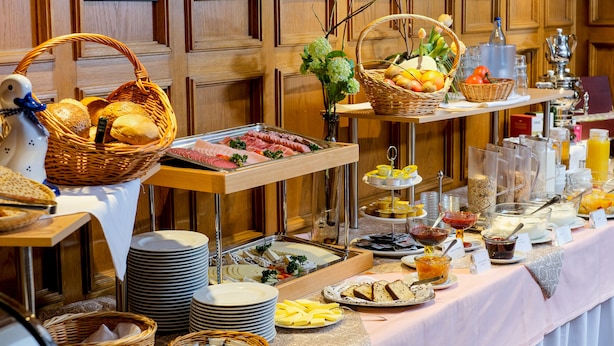 A buffet with various food items, including meats, cheeses, fruits, and beverages.