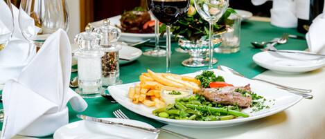 Una mesa de comedor dispuesta con platos de comida, copas de vino y cubiertos.
