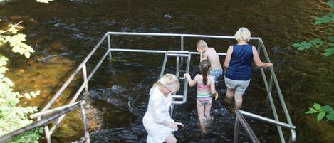 A metal structure over a stream with people standing on it.