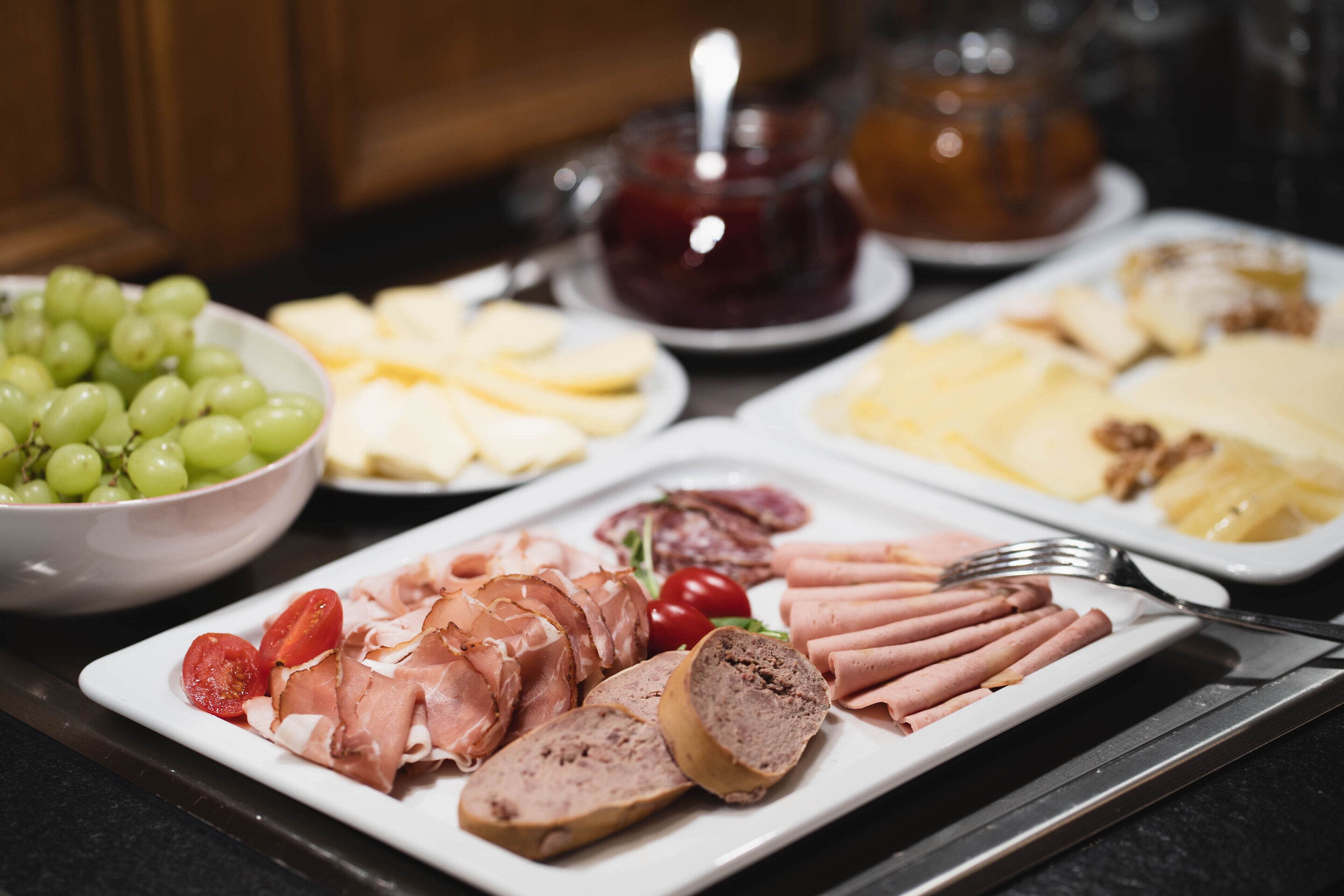 A charcuterie board with various meats, cheeses, and fruits.