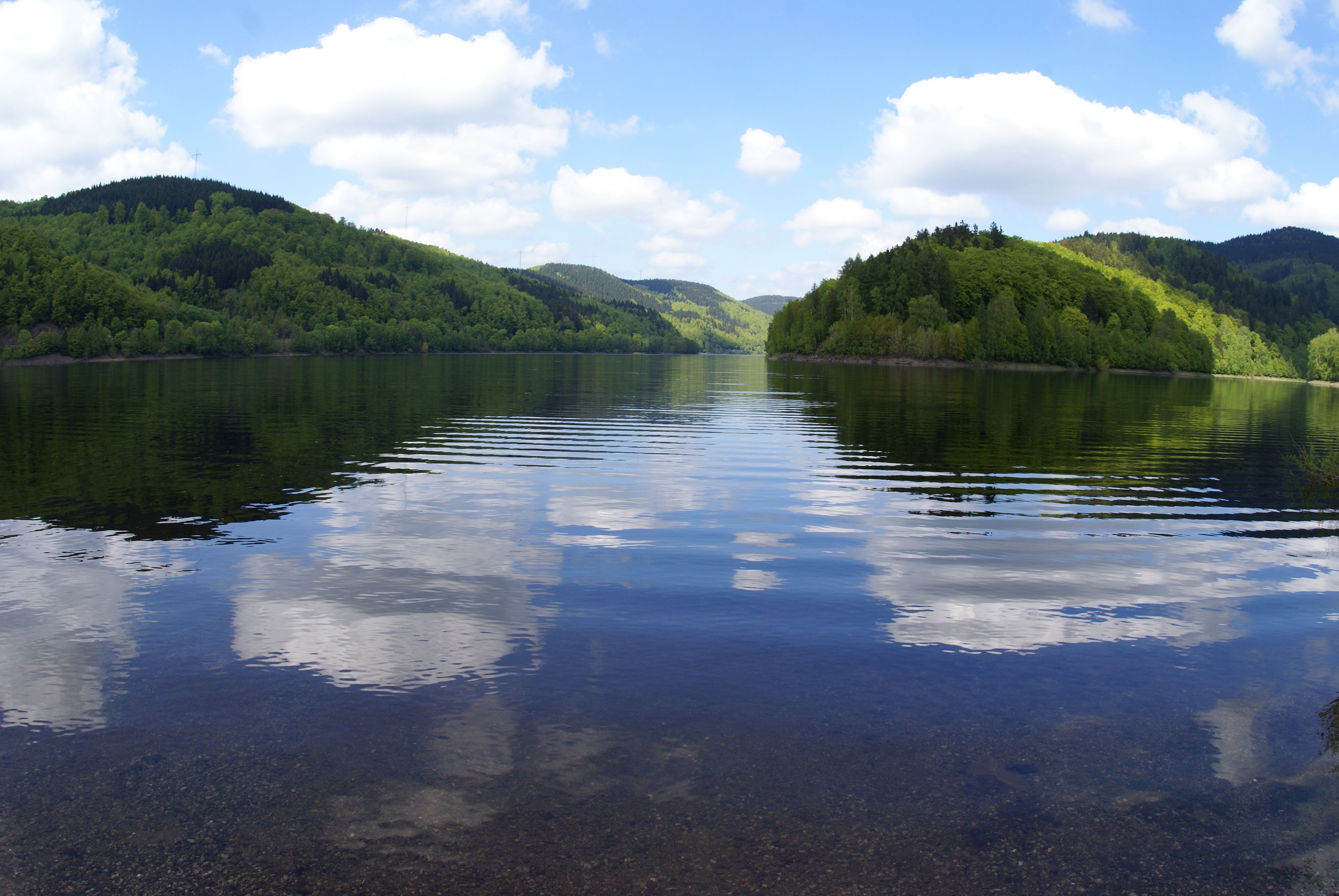 Un lago tranquilo rodeado de colinas boscosas.